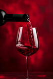 Red wine pouring in glass on red background. Glass of wine with bottle. Drink for celebrating, date, family dinner, party. Wine shop, wine tasting concept, copy space. Minimal winery banner