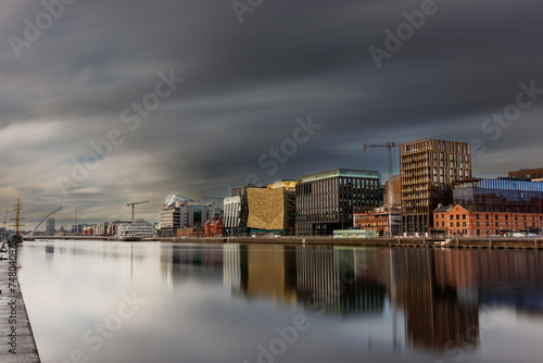 Dublin, Ireland, Dockland, modern building business center cityscape by Liffey river view during sunny day with tall ship and Samuel Beckett bridge in background. europe