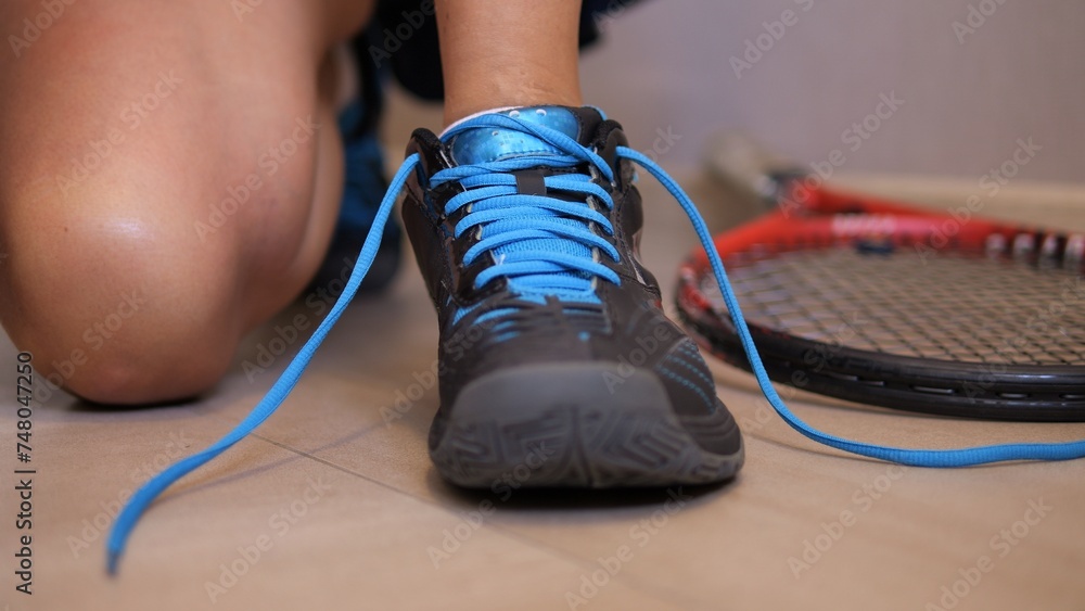 Observe preparation of woman as she carefully laces up her tennis shoes preparing for exciting tennis match This engaging footage provides intimate look into her dedication and focus on tennis court - obrazy, fototapety, plakaty 