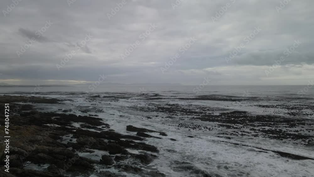 Hermanus Coast line fly over across wild waves and stone beach site with cloudy background Hermanus Coast line fly over across wild waves and stone beach site with cloudy background
