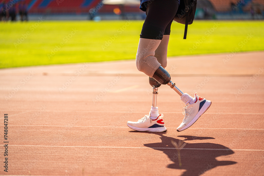 Asian para-athlete relaxes and Warm-up runner prosthetic leg on the track alone outside on a stadium track Paralympic running concept. Asian para-athlete relaxes and Warm-up runner prosthetic leg on the track alone outside on a stadium track Paralympic running concept.