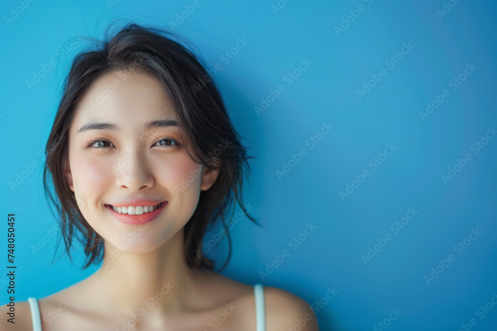 Empty space and a young Asian woman smiling blue background. Empty space and a young Asian woman smiling blue background.
