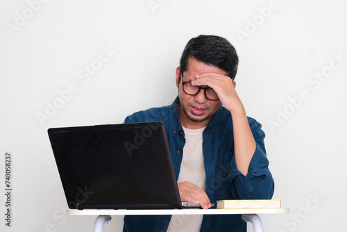 Adult Asian man got headache when sitting in front of a laptop photo