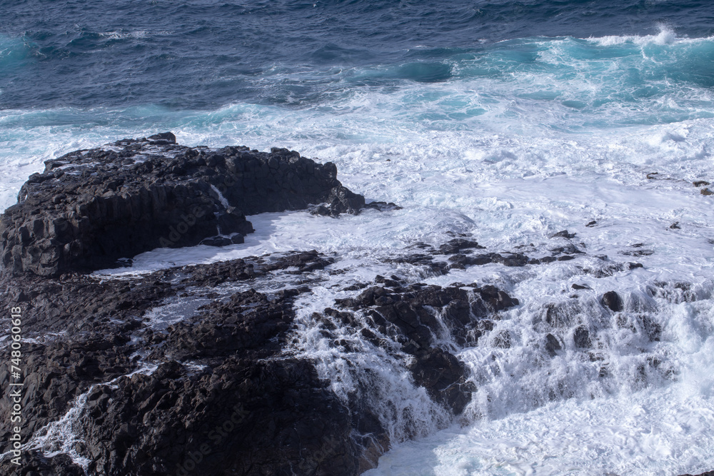 Craggy coastal scenery with waves crashing against the rocks on a windy, sunny day