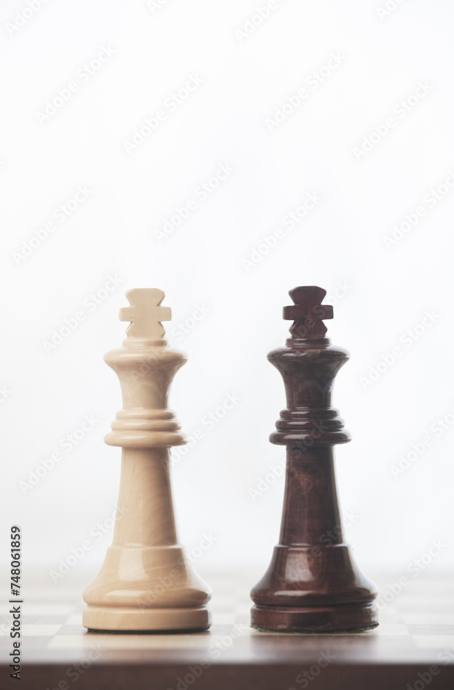CHESS PIECES OF WHITE KING AND BLACK KING FACING EACH OTHER, ON TOP OF CHESSBOARD CHESS PIECES OF WHITE KING AND BLACK KING FACING EACH OTHER, ON TOP OF CHESSBOARD