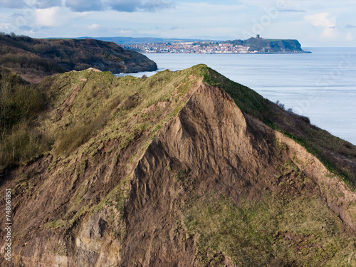 Aerial shot of UK coastline, North Yorkshire cliffs with Scarborough town and castle in the distance.