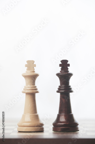 CHESS PIECES OF WHITE KING AND BLACK KING FACING EACH OTHER, ON TOP OF CHESSBOARD