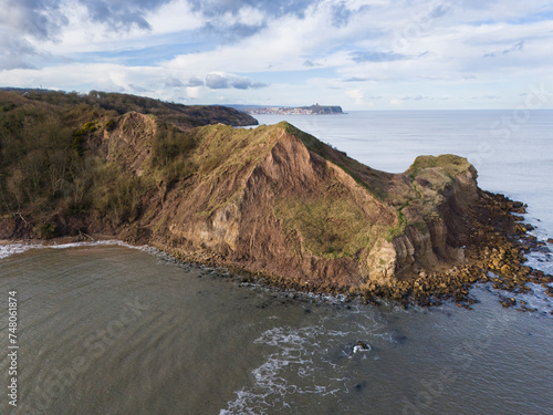 Aerial shot of UK coastline, North Yorkshire cliffs with Scarborough town and castle in the distance.