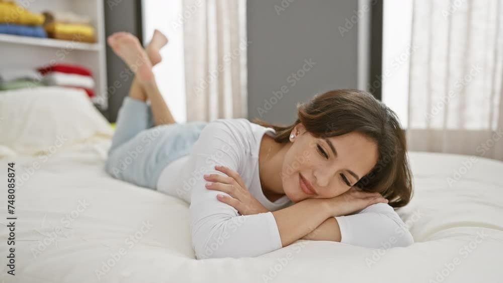 Portrait of a relaxed young hispanic woman lying on her stomach on a bed in a well-lit bedroom setting, exuding casual beauty and comfort. Portrait of a relaxed young hispanic woman lying on her stomach on a bed in a well-lit bedroom setting, exuding casual beauty and comfort.