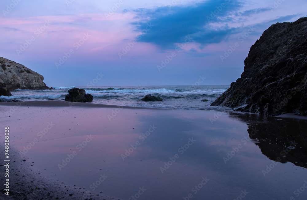 Waves crashing on a beach on the background of pinkish sky 