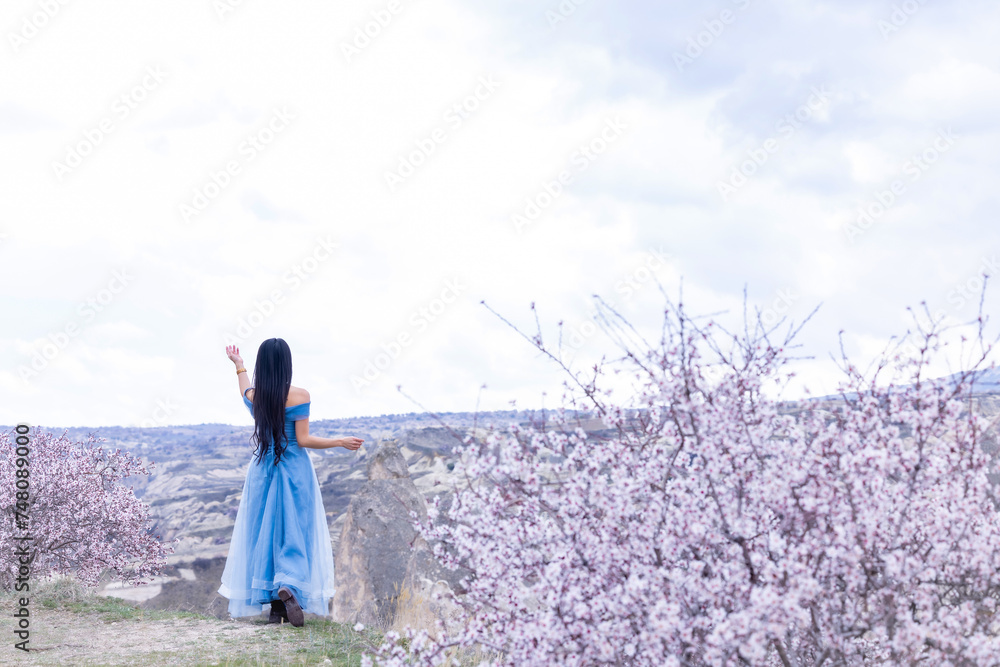 Beautiful woman in blue dress on Turkey rocks mountain.Cheerful woman relax outdoor with beautiful sky and pink flowers in holiday vacation.Woman tourist enjoy amazing mountain view.Travel and freedom Beautiful woman in blue dress on Turkey rocks mountain.Cheerful woman relax outdoor with beautiful sky and pink flowers in holiday vacation.Woman tourist enjoy amazing mountain view.Travel and freedom