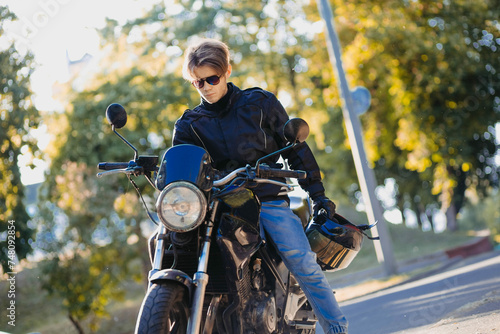 motorcyclist in outfit with motorcycle in sunglasses and jeans in summer