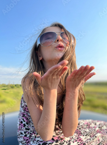 Air kiss. Cute girl sends an air kiss. Happy child enjoying summer and sun.
