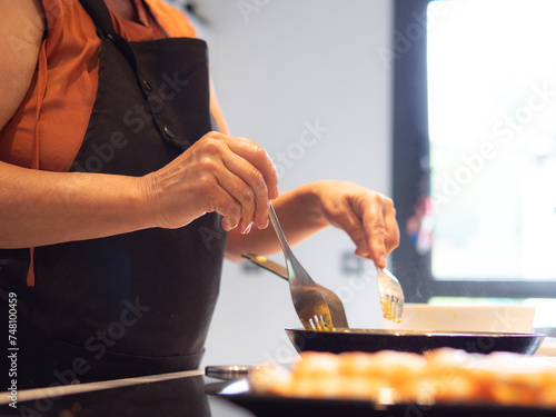 anonimous senior woman cooking fried fish photo