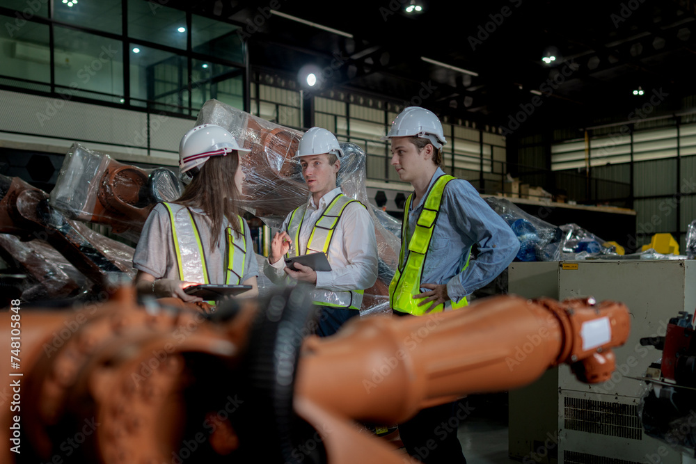 team engineers inspecting on machine with smart tablet. Worker works at heavy machine robot arm. The welding machine with a remote system in an industrial factory. Artificial intelligence concept.