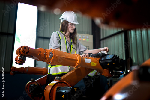 Factory engineers inspecting on machine with smart tablet. Worker works at heavy machine robot arm. The welding machine with a remote system in an industrial factory. Artificial intelligence concept.