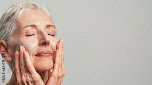 Portrait of beautiful mature woman with closed eyes touching her face, copy space © MFlex