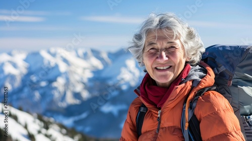 A smiling senior woman enjoys a scenic winter hike in the mountains © Maelgoa