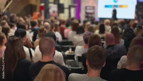 Audience attentively listens to female speaker at entrepreneurship conference. Diverse group of people engaged in start-up seminar. Ideal for topics on youth entrepreneurship, business incubators