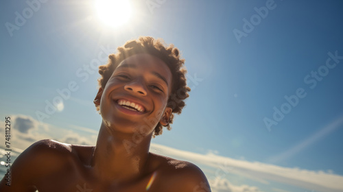 a young african american teenage happily enjoying himself on a sunny beach during a warm day.