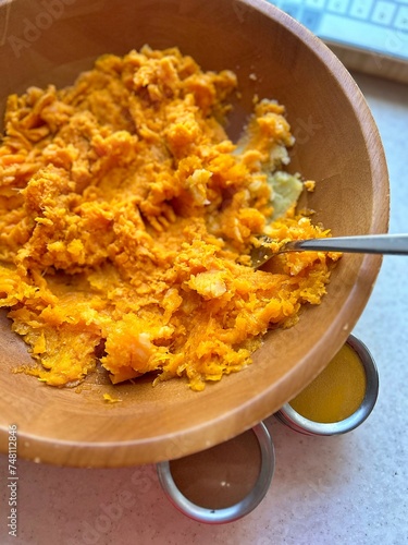 boiled pumpkin and potatoes, crushing pumpkin and potatoes in a wooden bowl, preparing pumpkin puree, spices in containers