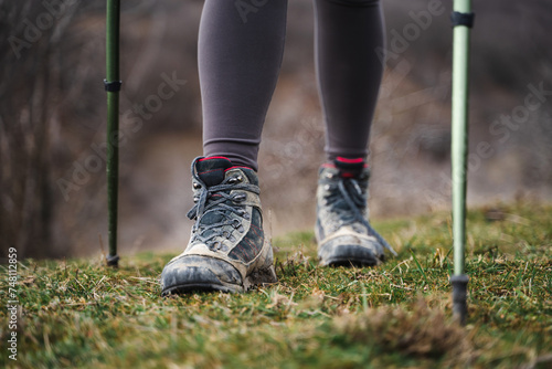 Closeup of low angle view of female legs in hiking shoes walking on a trail, traveler with trekking poles, tourism, sports, active lifestyle concept
