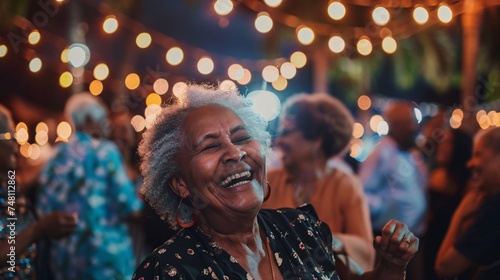 Elderly woman laughing as she dances with friends under the stars at an outdoor concert