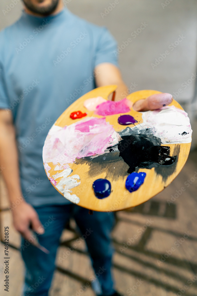 close up in an art studio an artist stands directly at the camera and show palette and