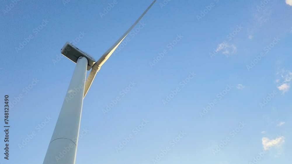Wind generator against a blue sky with clouds. Rotation of white wind turbine blades Wind generator against a blue sky with clouds. Rotation of white wind turbine blades