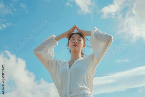 Invigorating stretches by an Asian woman under the expansive blue sky pastel hued backdrop for text