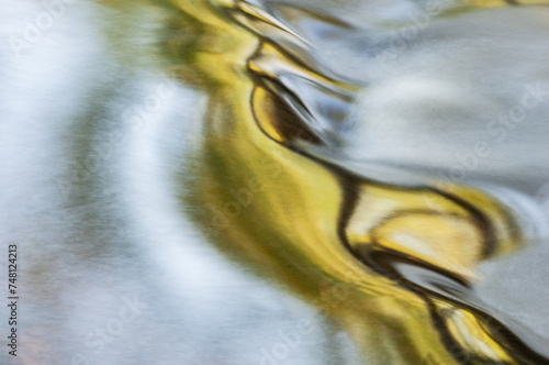 Landscape of the Portage Creek rapids captured with motion blur and illuminated by reflected color from sunlit trees and blue sky overhead, Michigan, USA photo