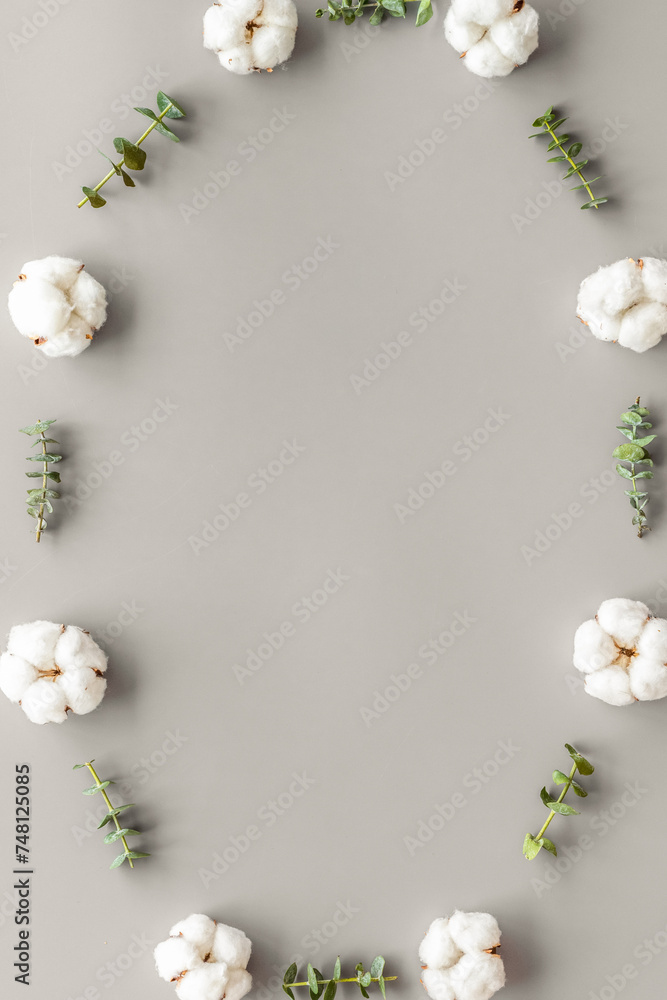 Flowers frame with fresh eucalyptus branches and cotton on grey background top view space for text Flowers frame with fresh eucalyptus branches and cotton on grey background top view space for text