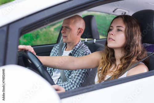 Confident young woman driving car with her husband in passenger seat on sunny spring day. Family road trip or daily commuting concept © JackF
