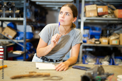 Satisfied female employee of hardware store makes notes in a notebook