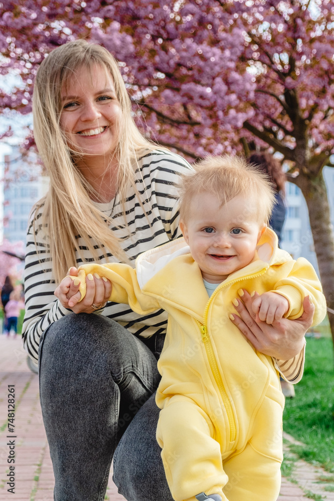 Obraz premium Learning to walk among cherry blossom trees with mom.