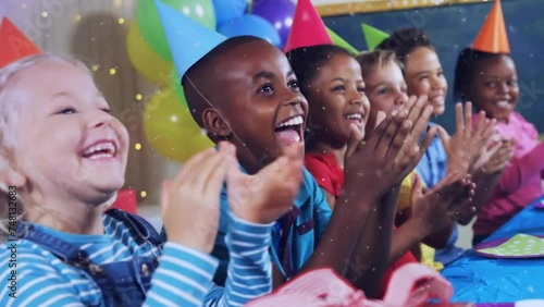 Animation of gold confetti falling over happy diverse children clapping at birthday party photo