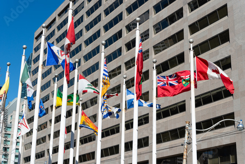 lackadaisical provincial and territorial flags of canada flying in the wind in downtown toronto