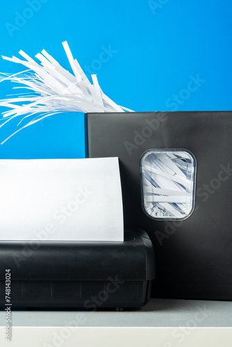 Office paper shredder on blue studio background