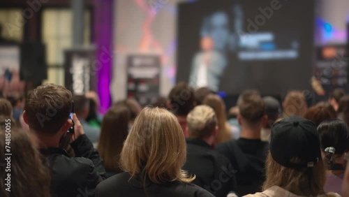 Entrepreneurs gather, attentively listening to success stories at a youth-led business workshop. Millennial crowd focuses on speaker at an entrepreneurship conference, fostering startup innovation.