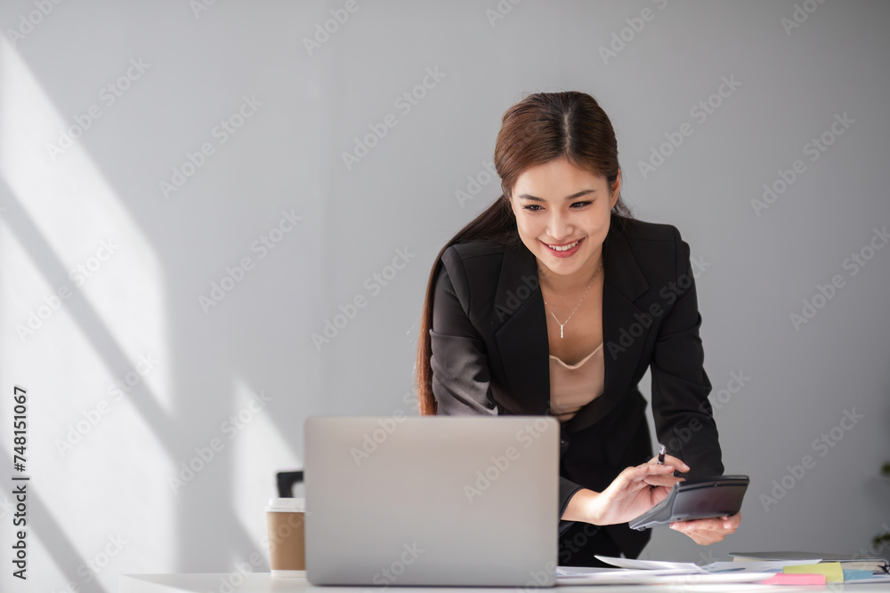 Businesswoman using laptop and mobile phone talking about work and managing company business Businesswoman using laptop and mobile phone talking about work and managing company business