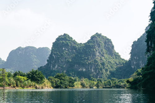 Landscape views of limestone mountains, reflective water and lush greenery of Tran An. A popular spot for tourist to take boat rides while in Northern Vietnam. © Chris