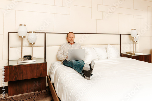 older senior man relaxing working on his laptop computer in a hotel room © david