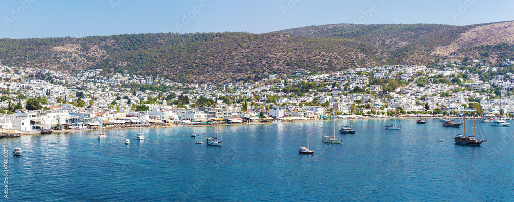 View to the part of Bodrum on the hillside, beach and the sailboats in the harbor. Detailed panorama of the bay. Bodrum, Turkey