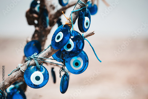 Traditional Turkish amulet Evil Eye or blue eye (Nazar boncugu) on tree brunch. Traditional Turkish amulet and souvenir. Close up, defocused background, copy space. Cappadocia, Turkiye (Turkey)