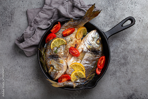 Roasted sea bream with lemon, tomatoes and herbs in pan photo