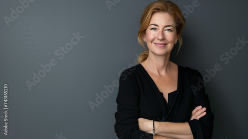 Retrato de empresária madura com os braços cruzados em pé contra um fundo cinza photo