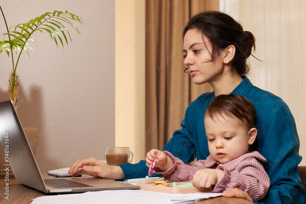 beautiful businesswoman working on laptop with her little child girl at home beautiful businesswoman working on laptop with her little child girl at home
