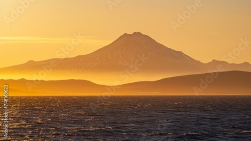 As the sun sets over the horizon the contrast between a towering mountain peak and the endless expanse of the sea is highlighted in a stunning display of light and shadow © Justlight