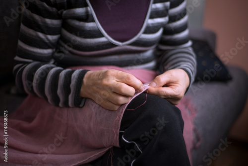 Senior woman hands sewing detail close up