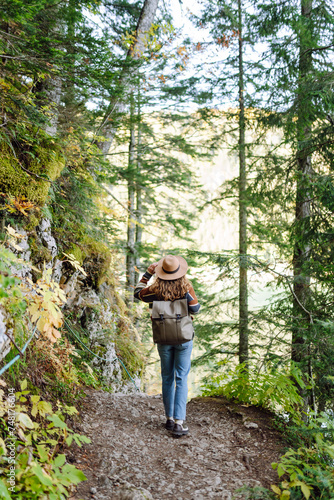 Young woman with backpack walking in beautiful  forest. Hiking and leisure theme.